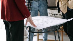 Arquitectos revisando planos de una reforma integral en una mesa durante la planificación de un proyecto de vivienda.